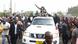 Tundu Lissu waves to a crowd from the back of an open car in Dar es Salaam